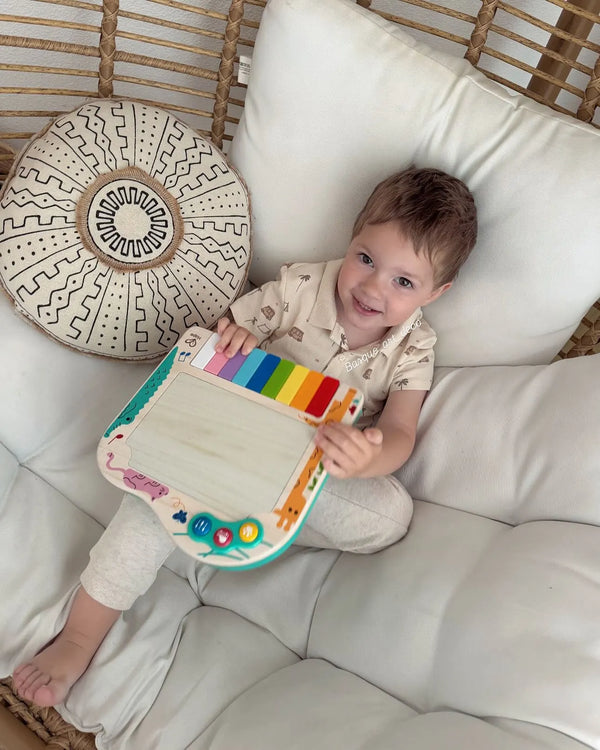 Bebê sentado na almofada brincando com o piano de pixels Hape