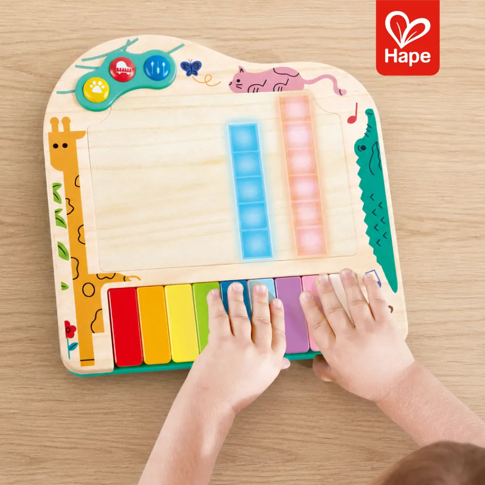 Criança tocando as teclas do piano de pixels Hape com as luzes da tela acesas